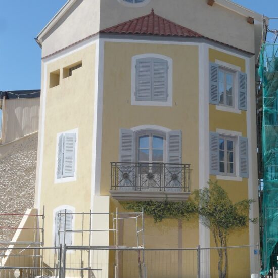 Vue de la réalisation du trompe-l'oeil sur la façade d'un immeuble à Chatte