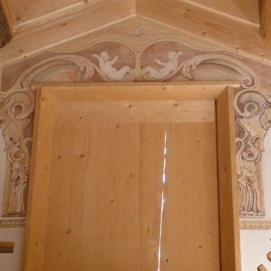 L'encadrement d'une fenêtre en bois orné de volutes et d'animaux en trompe-l'oeil